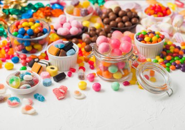 Kavanozda pembe lolipop şekerlemeleri çeşitli sütlü çikolata ve jöleli sakızlı şekerler üzerine beyaz meyankökü ve çilekli şekerler.