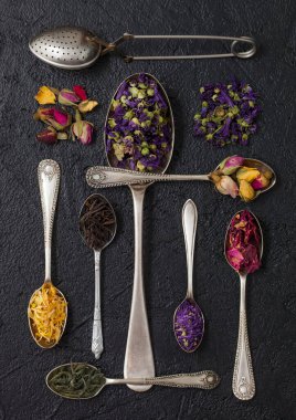 Farklı kaşıklarda siyah üzerine klasik ve bitkisel çay. Üst görünüm