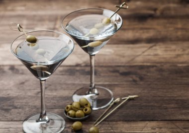 Orijinal bardaklarda votka martini cin kokteyli metal kasede zeytin ve tahta arka planda bambu çubukları.. 