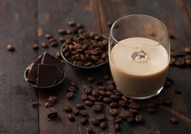 Bir bardak İrlanda kremalı baileys likörü, kahve çekirdekleri ve koyu ahşap kaplama çelik kasede koyu çikolata. Üst görünüm