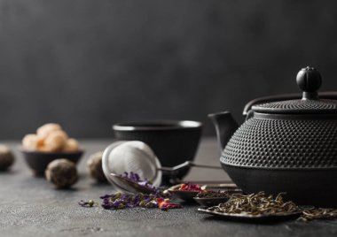 Şekerli yeşil ve siyah çay ve kaşıklı Çin çaydanlığı ve siyah arkaplanda kaşık ve kaşık.