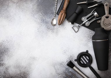Çeşitli kokteyl aletleri. Bakır jigger, siyah karıştırıcı, karıştırıcı ve süzgeçli kaşık ve siyah kauçuk tepside..