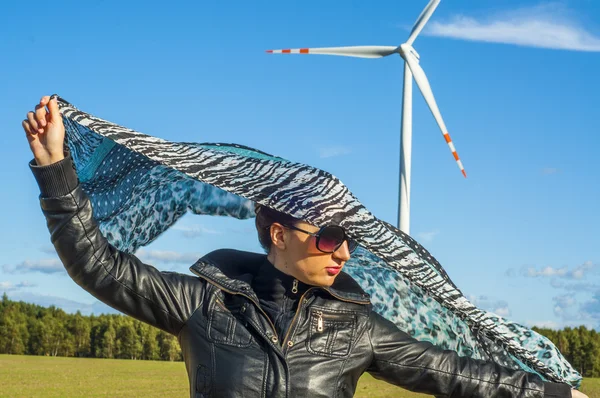 Niña sosteniendo lona-capa y turbina de viento en el fondo —  Fotos de Stock