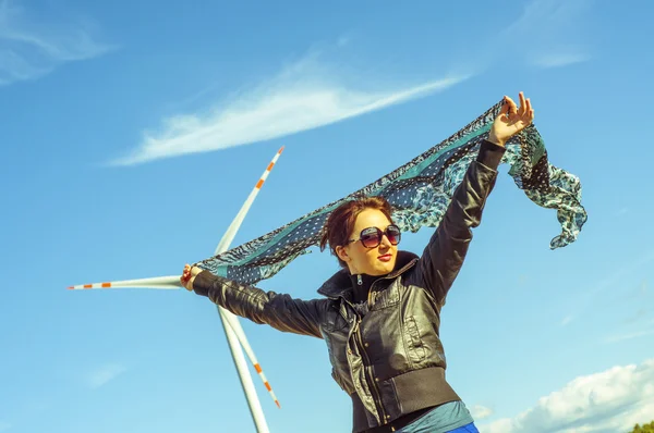 Girl holding canvas-cape and windturbine in background — Stock Photo, Image