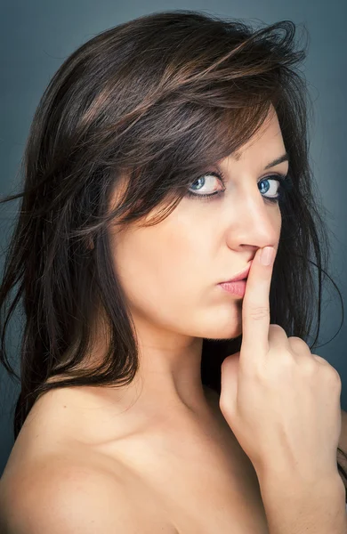 Retrato de uma bela morena com um dedo nos lábios mostrando para manter o silêncio — Fotografia de Stock