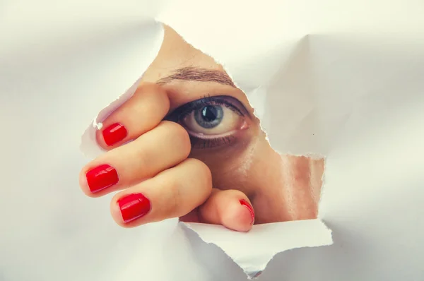 Woman looking through paper hole — Stock Photo, Image