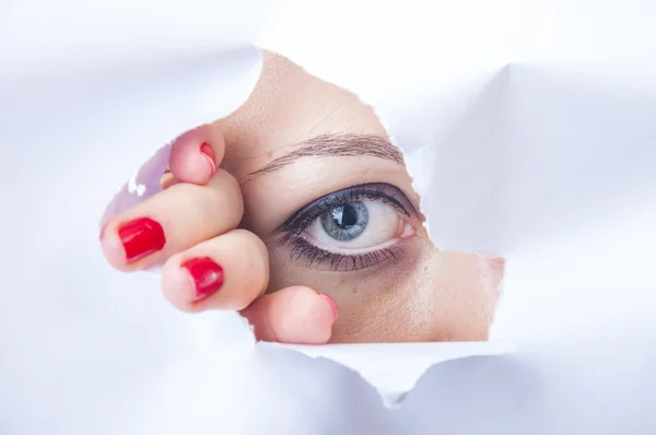 Mujer mirando a través de agujero de papel — Foto de Stock