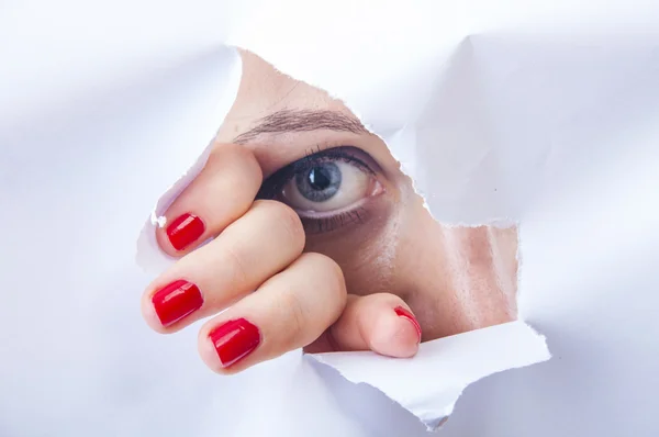Mujer mirando a través de agujero de papel — Foto de Stock