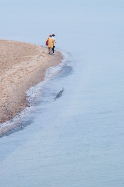 Kumsalda yürüyen turistler