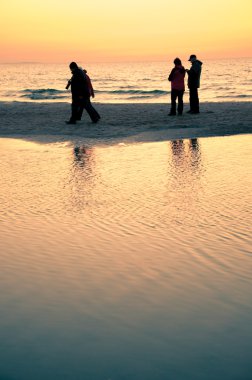 Kumsalda yürüyen turistler
