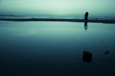 Kumsalda yürüyen turistler