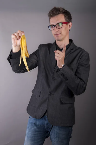 Young businessman holds a banana peel — Stock Photo, Image