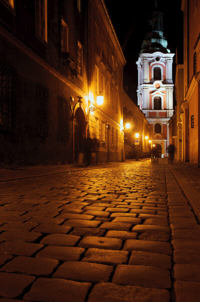 Street with church by night in Poznan, Poland