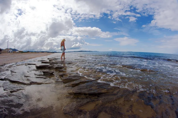 La ragazza su una spiaggia rocciosa — Foto Stock