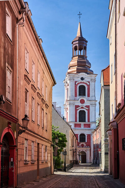 Cobbled street and historic belfry of a baroque church in the city of Poznan