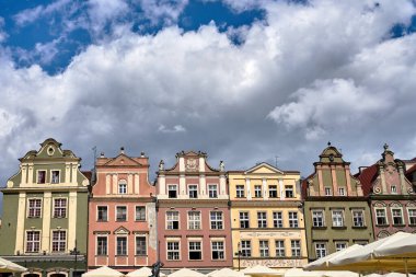 Tarihi apartman binalarının cepheleri ve restoranın şemsiyeleri Poznan 'daki Eski Pazar Meydanı