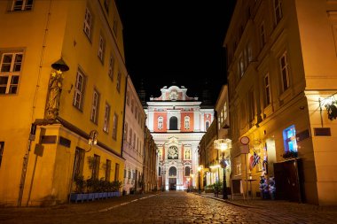 Poznan 'da akşam saatlerinde sütunlar ve heykellerle süslenmiş bir barok kilisesinin cephesi.