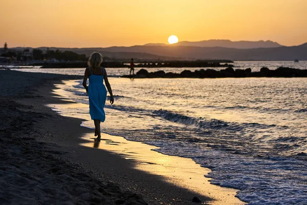 希腊克里特岛上的一个身着夏装的女孩在日落时分躺在沙滩上 — 图库照片