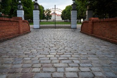 Rogalin 'deki barok sarayına giden kaldırımlı yol ve metal kapı.