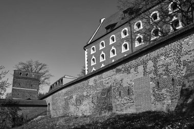 a historic defensive wall with a brick tower in the city of Torun in Poland, monochrome