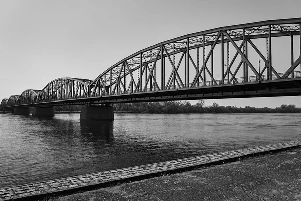 The Vistula River and the steel structure of the road bridge in the city of Torun, Poland, monochrome