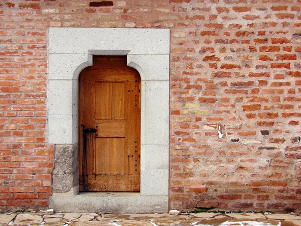 Porta de madeira antiga na parede do castelo de tijolo — Fotografia de Stock