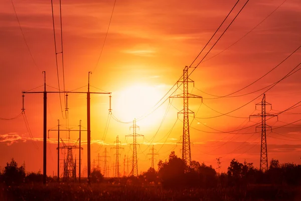 Enerji krizi: günbatımının arka planında rahatsız edici kırmızı tonlarda elektrik hatları 