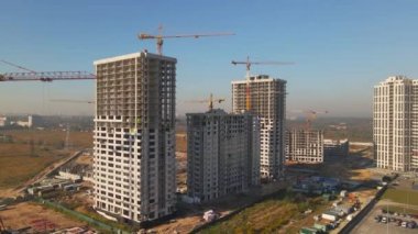 Vinçleri olan bir inşaat alanı. Hava kamerası yeni binaların beton çerçevelerine yaklaşıyor.