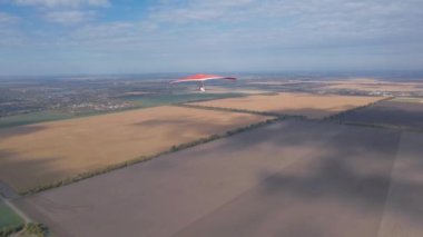 Tarlaların üzerinde kırmızı planör. Hava aracı görüntüleri.