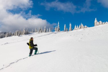 Yürüyüşçü dağlardaki kar çölünü keşfeder. Derin karda yolda bir adam var. Açık hava aktivitesi için güzel bir kış günü..