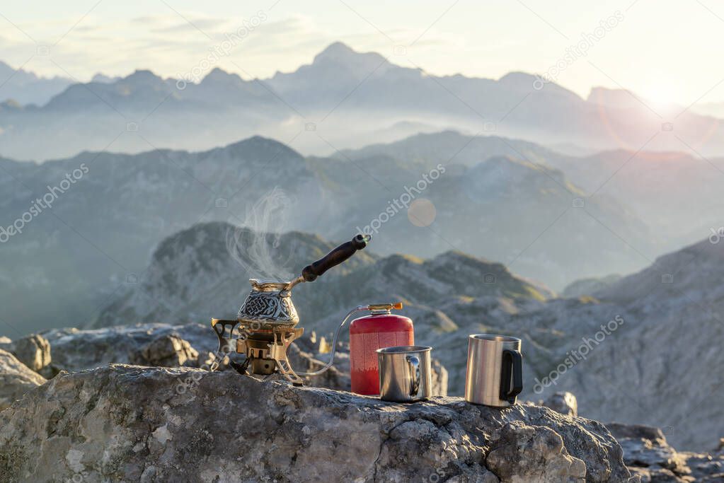 Vapouring coffee pot on the touristic stove and metal mugs on the stone with amazing mountain view. Julian Alps, Soca valley, Slovenia