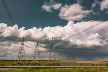 Dramatik gökyüzüne karşı elektrik hatları. Güç hattı direkleri olan kırsal alan.