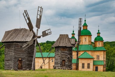 Old wooden church and windmills in the Pirogovo skansen, Kyiv, Ukraine. Traditional wooden architecture of Ukraine