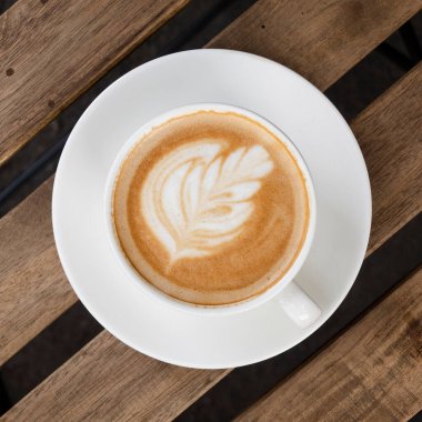 Cappuccino cup with beautiful floral coffee art, top view