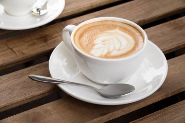 Morning cappuccino cup on a wooden table in a street cafe