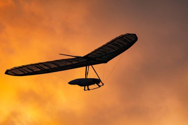 Sport hang glider wing silhouette on the burning sunset sky