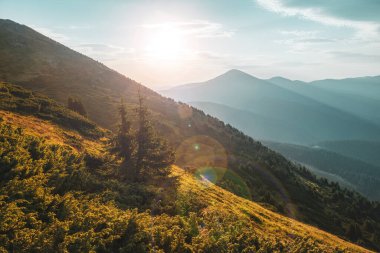 Dağlarda güzel bir gündoğumu. Yükselen güneşle aydınlatılan uzun gölgeli tepeler.. 