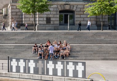 Youth tourist group on a memorial for the victims of the wall clipart