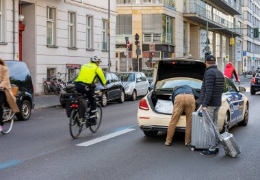 Berlin 'de taksi şoförü yolcularının bagajlarını yüklüyor.