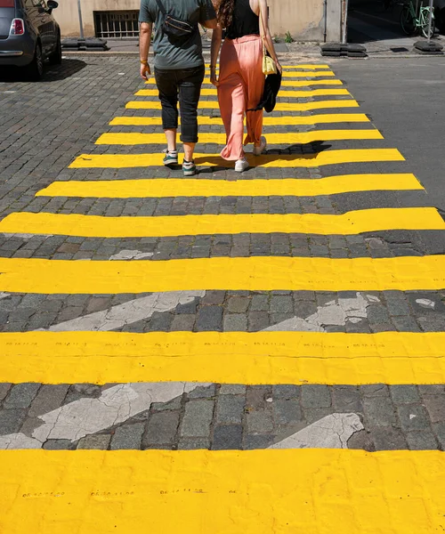 Passers-by and pedestrians cross a pedestrian crossing marked in yellow, Berlin, Germany