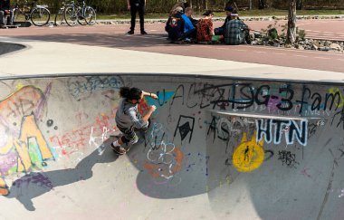 Skateboard and cyclists in a skate pool in the amusement park at Gleisdreieck Park in Berlin-Mitte, Germany