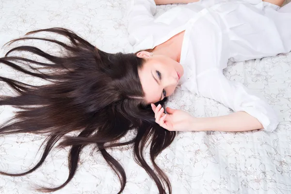 Portrait of brunette woman on the bed. — Stock Photo, Image