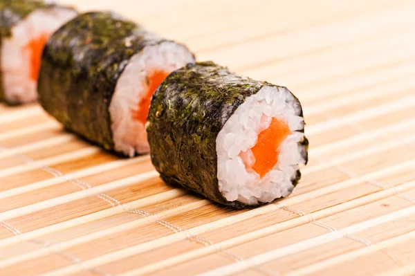 Close-up de sushi em linha na esteira de bambu — Fotografia de Stock