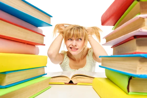 Tired woman sitting at the desk surrounded with piles of books — Stock Photo, Image