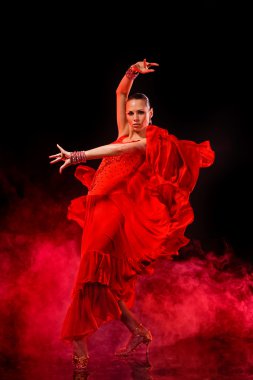 Young woman dancing Latino on dark smoky background