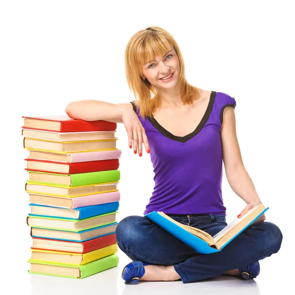 Schöne Studentin sitzt auf einem Fußboden mit einem Stapel Bücher, isoliert lizenzfreie Stockbilder