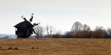 Eski bir rüzgâr mili silueti ve ufukta ağaçlar olan bir manzara. Ulusal Açık Hava Halk Mimarisi Müzesi Pirogovo. Ukrayna, Kiev, Mart 08, 2019
