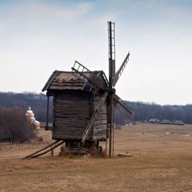 Tarlada eski bir rüzgâr mili ve kilise büyüklüğünde bir manzara. Ulusal Açık Hava Halk Mimarisi Müzesi Pirogovo. Ukrayna, Kiev, Mart 08, 2019