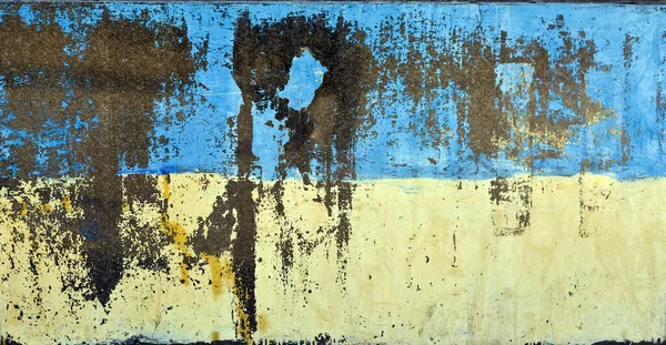 Wall element in the urban infrastructure of Kyiv, grunge painted in the colors of the national flag of Ukraine. Blue and yellow