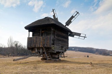 Tarlada eski bir rüzgâr mili ve kilise büyüklüğünde bir manzara. Ulusal Açık Hava Halk Mimarisi Müzesi Pirogovo. Ukrayna, Kiev, Mart 08, 2019